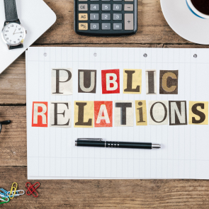 Public Relations title from newspaper cutout letters on paper notepad